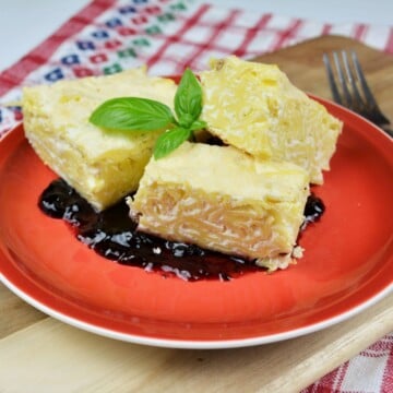 Sweet Noodle Kugel With Raisins Served on Plate With Blueberry Jam on Bottom