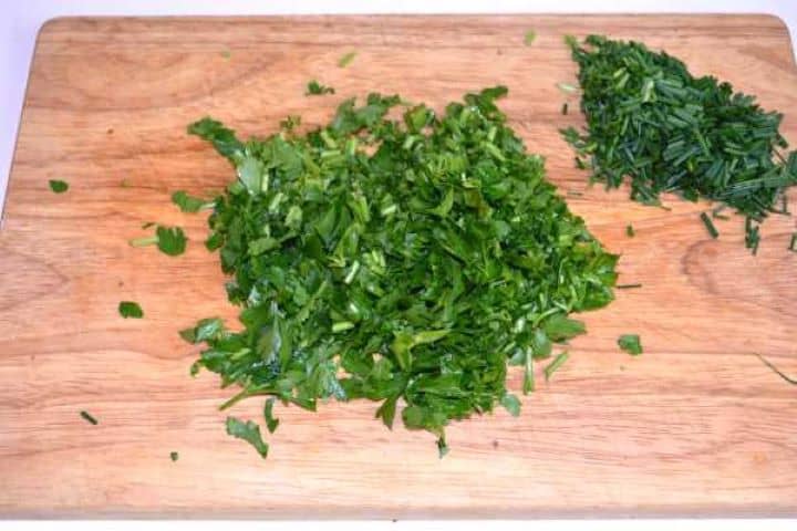 Chopped Parsley Chopped parsley and chives on the chopping board.