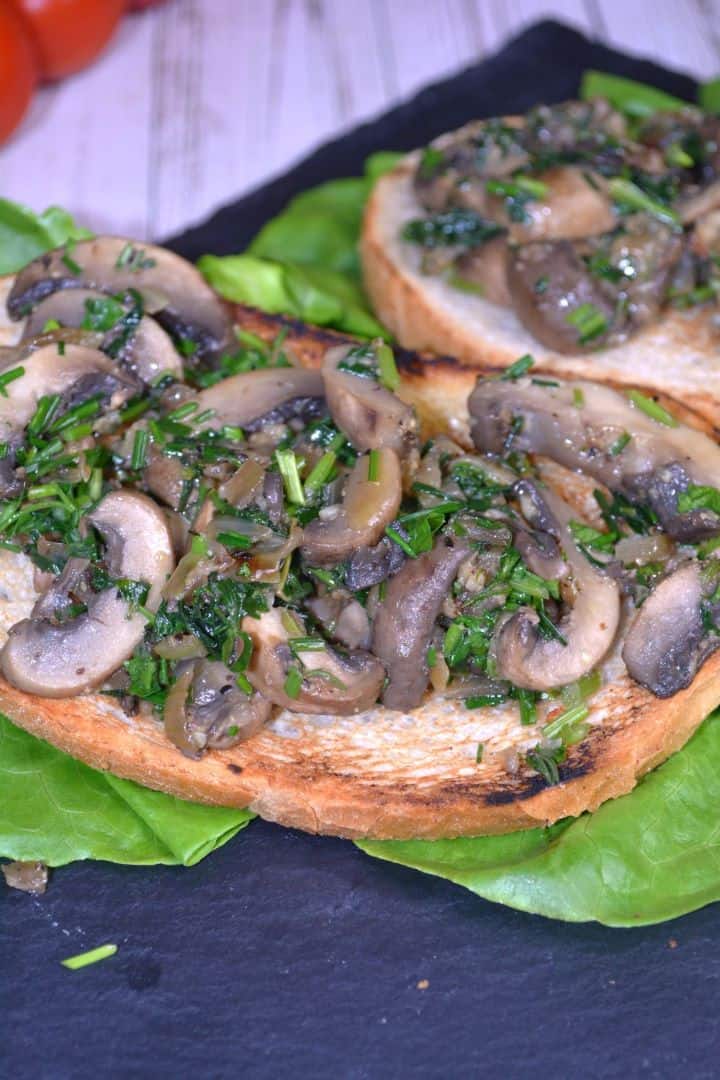 Serving Sautéed vegan garlic mushrooms served on a plate with toasted crusty bread, crisp lettuce, and cherry tomatoes.