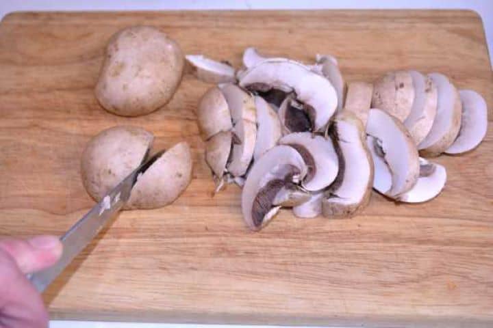 Sliced Mushrooms Fresh white button mushrooms roughly sliced on a wooden chopping board.