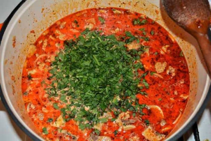 Pouring double cream and fresh parsley into pork mince and mushrooms for a rich pasta sauce.
