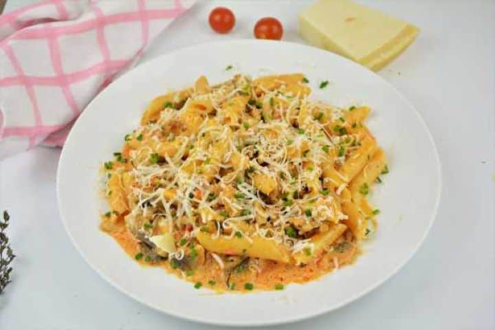 Plate of creamy Hungarian-inspired ground pork pasta garnished with grated Parmesan and fresh chives