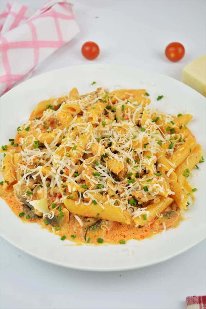 Creamy pork mince pasta with mushrooms served on a white plate topped with grated Parmesan and fresh parsley.