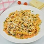 Creamy pork mince pasta with mushrooms served on a white plate topped with grated Parmesan and fresh parsley.