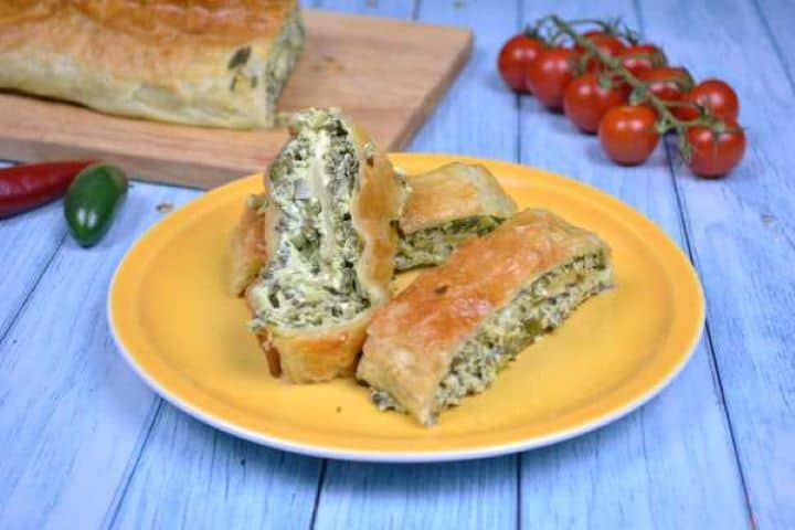 Slices of warm puff pastry spinach and feta rolls showing the creamy center on a plate.