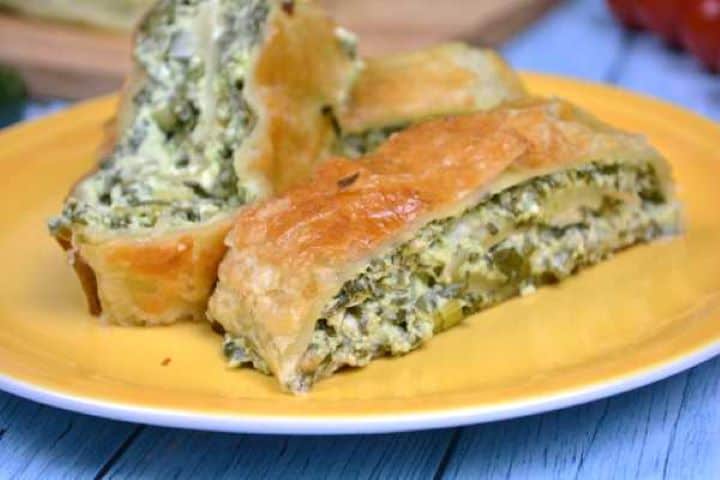 Close-up of three flaky spinach and feta roll pinwheels served as a savory appetizer.