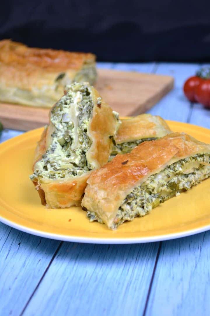 Crispy golden puff pastry spinach and feta rolls served on a yellow plate.