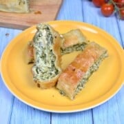 Crispy golden puff pastry spinach and feta rolls served on a yellow plate.
