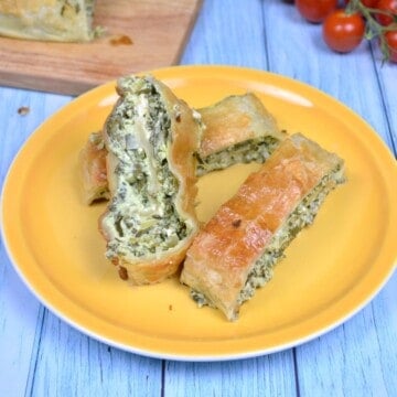 Crispy golden puff pastry spinach and feta rolls served on a yellow plate.