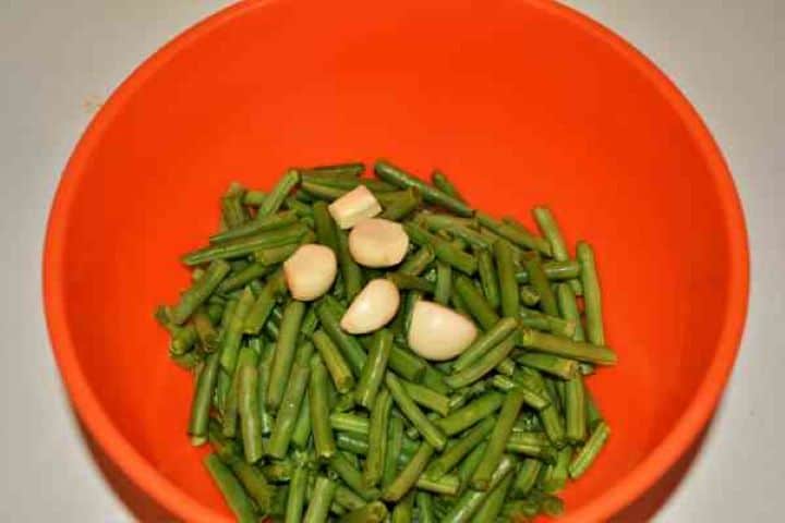 Green Bean Salad With Garlic Cream-Clean and Cut Green Beans and Peeled Garlic Cloves in the Bowl Cleaning fresh green beans and snapping them into bite-sized pieces for salad