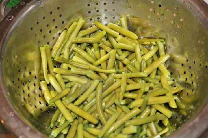 Boiled Green Beans Draining tender par-boiled green beans in a colander strainer.