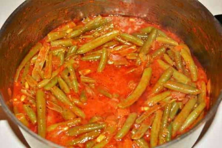 Ready Finished Greek green beans in tomato sauce simmering in a saucepan.