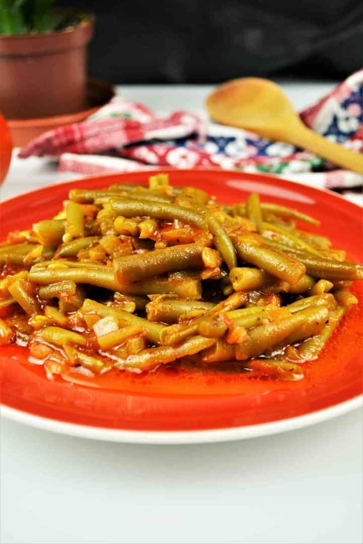 Serving Greek green beans in tomato sauce served on a white plate with fresh bread.