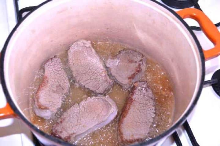 Other Side Turning seared beef slices to brown both sides evenly in the Dutch oven.