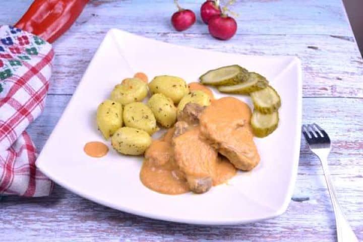 Tender slices of Hungarian beef hunter's stew coated in creamy vegetable sauce on a white plate.