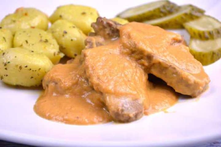 Served Homemade Hungarian hunter's stew plated with soft dumplings and garnished with pickles on a modern dinner plate.