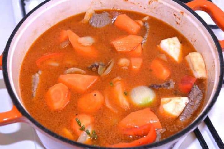 Simmering Simmering Hungarian beef stew covered in seasoned broth inside a Dutch oven.