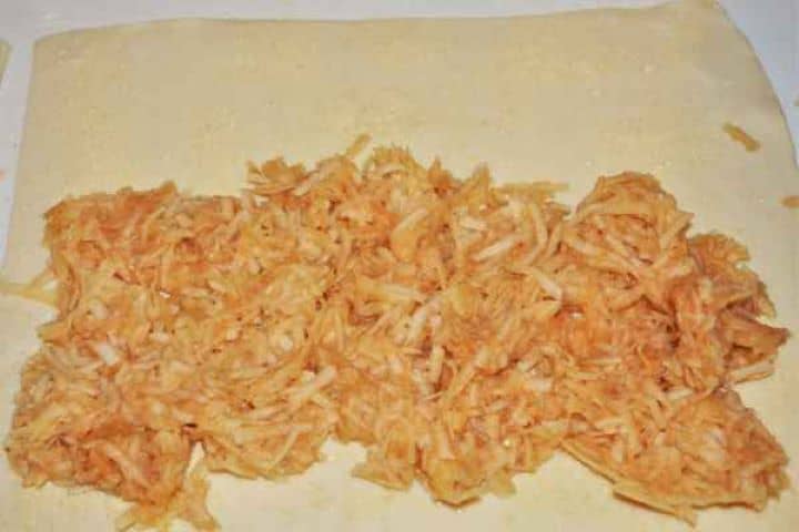 Apple Shortcrust Pastry Recipe-Grated Apple Filling on Shortcrust Pastry Spreading the squeezed grated apple filling over a shortcrust pastry sheet sprinkled with a moisture-absorbing layer of breadcrumbs.