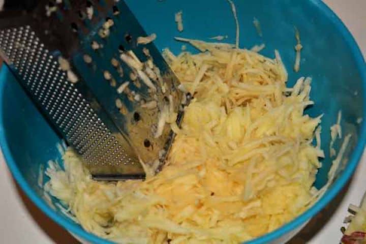 Apple Shortcrust Pastry Recipe-Grated Apples in the Bowl Coarsely grated apples mixed with ground cinnamon, sugar, and lemon juice in a bowl.