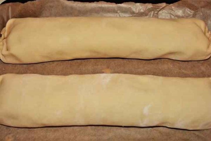 Apple Shortcrust Pastry Recipe-Rolled Shortcrust Pastry in the Baking Tray Tightly rolled apple shortcrust pastry logs with pinched seams sitting on parchment paper in a baking tray.