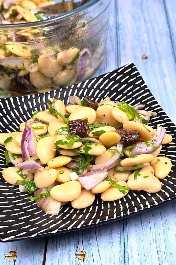 Easy butter bean salad served on a plate with red onion and sun-dried tomatoes
