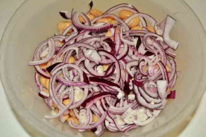 Butter Beans Salad Recipe-Sliced Red Onion on the Drained Beans in the Bowl Thinly sliced red onion layered over drained butter beans in a bowl.
