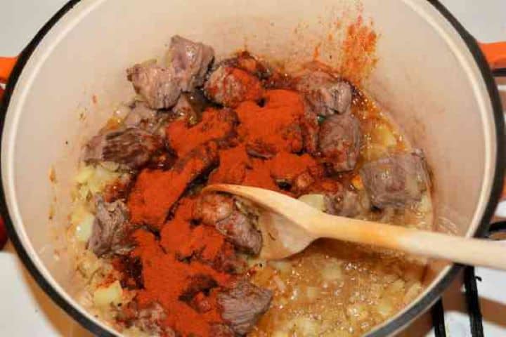 Dutch Oven Beef Stew-Paprika Powder Over the Fried Beef Cubes in the Dutch Oven Vibrant sweet Hungarian paprika powder sprinkled over seared beef and vegetables inside a Dutch oven pot.
