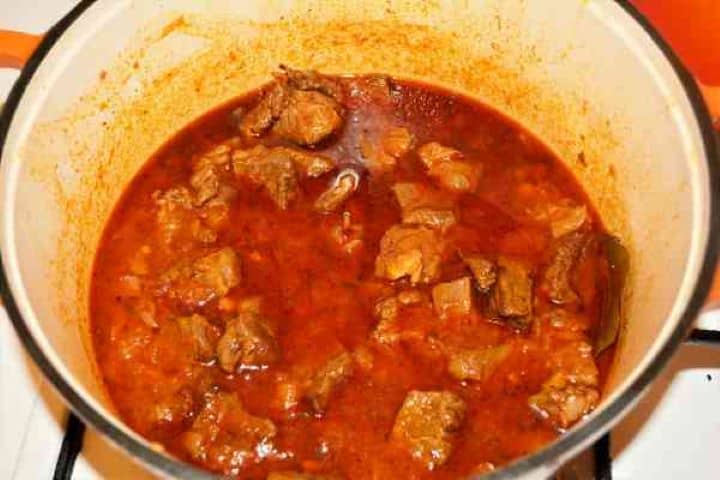Dutch Oven Beef Stew-Ready to Serve A thick, glossy Hungarian beef stew fully cooked and resting inside a cast iron Dutch oven pot.
