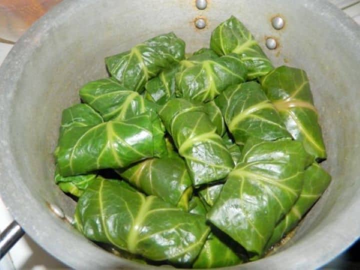 Uncooked stuffed collard greens arranged tightly in a neat circular pattern inside the pot.