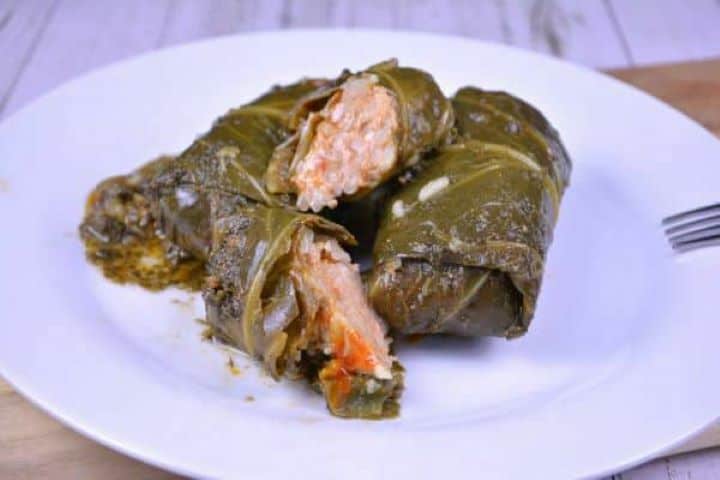 Plated Transylvanian stuffed collard greens recipe rolls topped with hot sorrel broth.