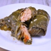 A white plate featuring a finished authentic stuffed collard greens recipe (Transylvanian Töltike) served with sour cream.