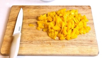 Finely diced canned peaches thoroughly drained on a cutting board.