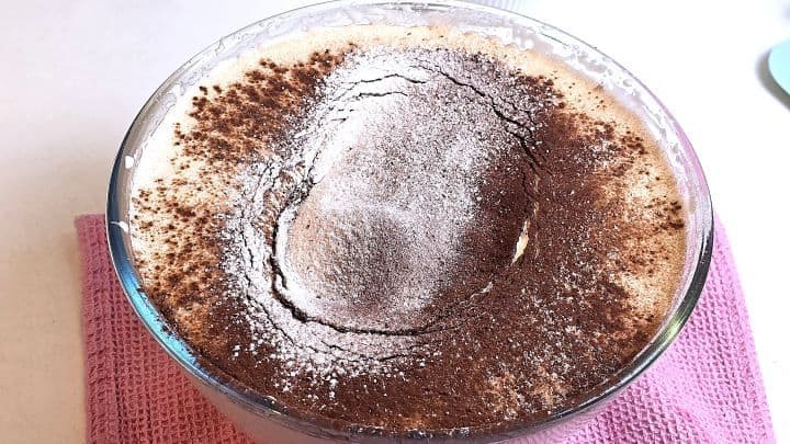 Sifting all-purpose flour and dark cocoa powder over whipped egg foam.