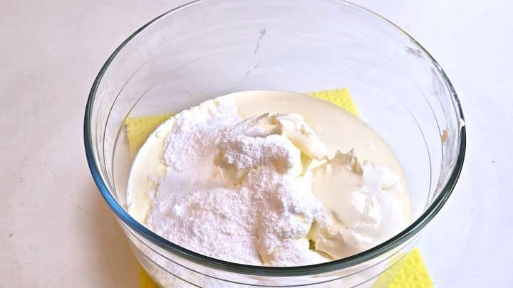 Combining mascarpone cheese, double cream, and powdered sugar in a mixing bowl.