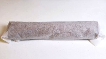 Warm chocolate sponge cake rolled into a loose cylinder with parchment paper to prevent cracking.