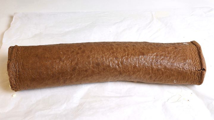 Rolling up the chocolate peach Swiss roll tightly using parchment paper.