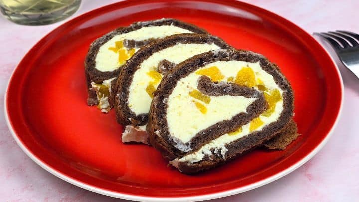 Elegant presentation of three peach mascarpone cake roll slices arranged on a festive red plate for a dinner party dessert.