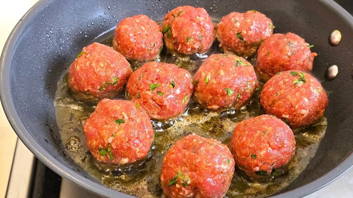 Searing the rolled beef meatballs in a non-stick frying pan with extra virgin olive oil.