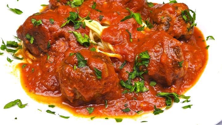 A close-up of authentic Romanian chiftele marinate garnished with a sprinkle of fresh chopped parsley.