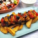 Mediterranean Chicken Kebabs Served on Plate With Fries Greek Salad and Tzatziki