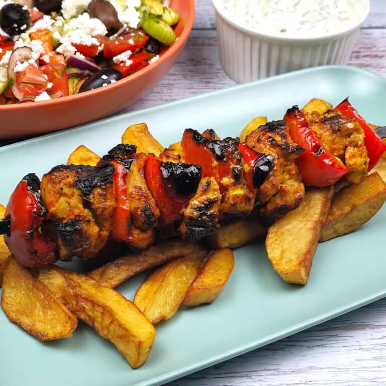 Mediterranean Chicken Kebabs Served on Plate With Fries Greek Salad and Tzatziki