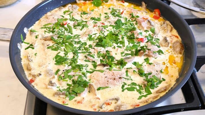 Chopped Parsley Over the Simmering Tenderloin Slices in the Creamy Sauce in the Pan