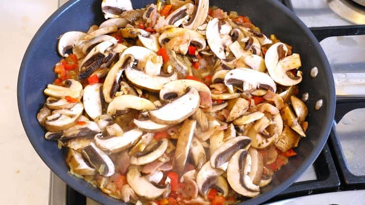 Sliced Mushrooms Over the Frying Red Pepper, Onion and Cut Smoked Bacon in the Pan