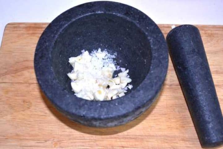 Salt Crushing fresh garlic cloves with coarse sea salt in a mortar and pestle to make a smooth paste.