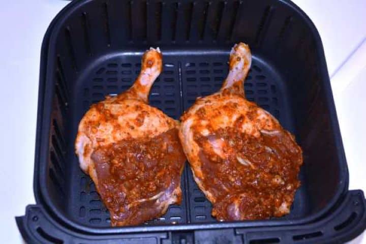 Basket Seasoned duck legs placed skin side down in an air fryer basket for the first rendering stage.
