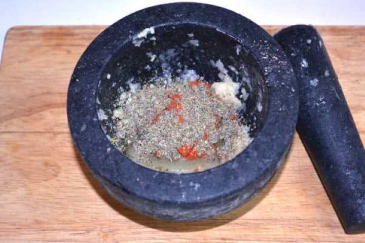 Spices Adding sweet paprika, black pepper, and dried marjoram to crushed garlic in a mortar.