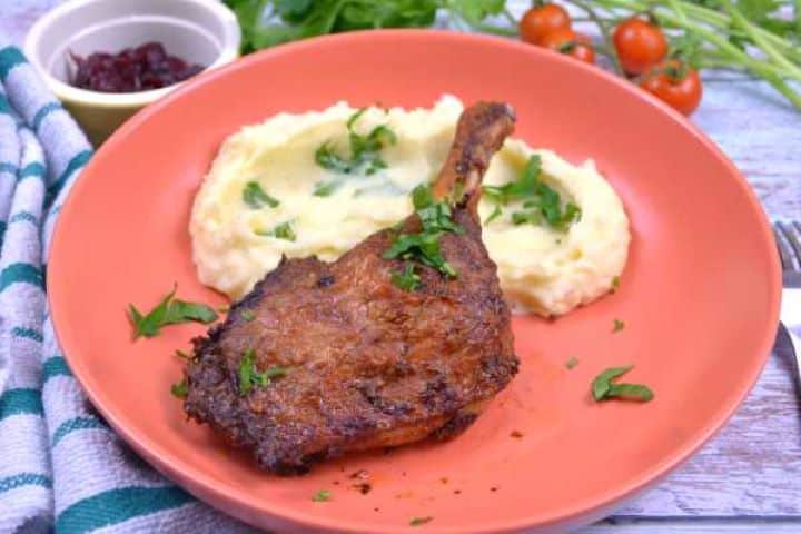 Serve Air fryer duck leg served on orange plate with mashed potatoes.