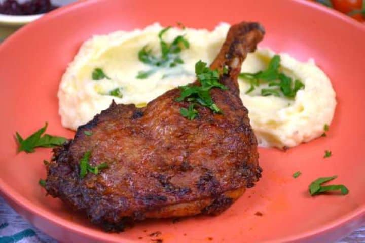 Served Tender juicy air fryer duck leg with crispy golden skin served on a white dinner plate.