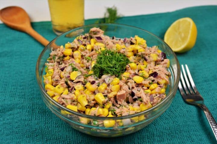 Served Healthy tuna corn salad served in a glass bowl with crusty fresh bread and a cold glass of beer.