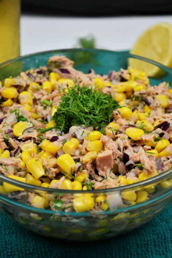 Serving Tuna corn salad with fresh dill and red onion served in a glass bowl without mayonnaise.